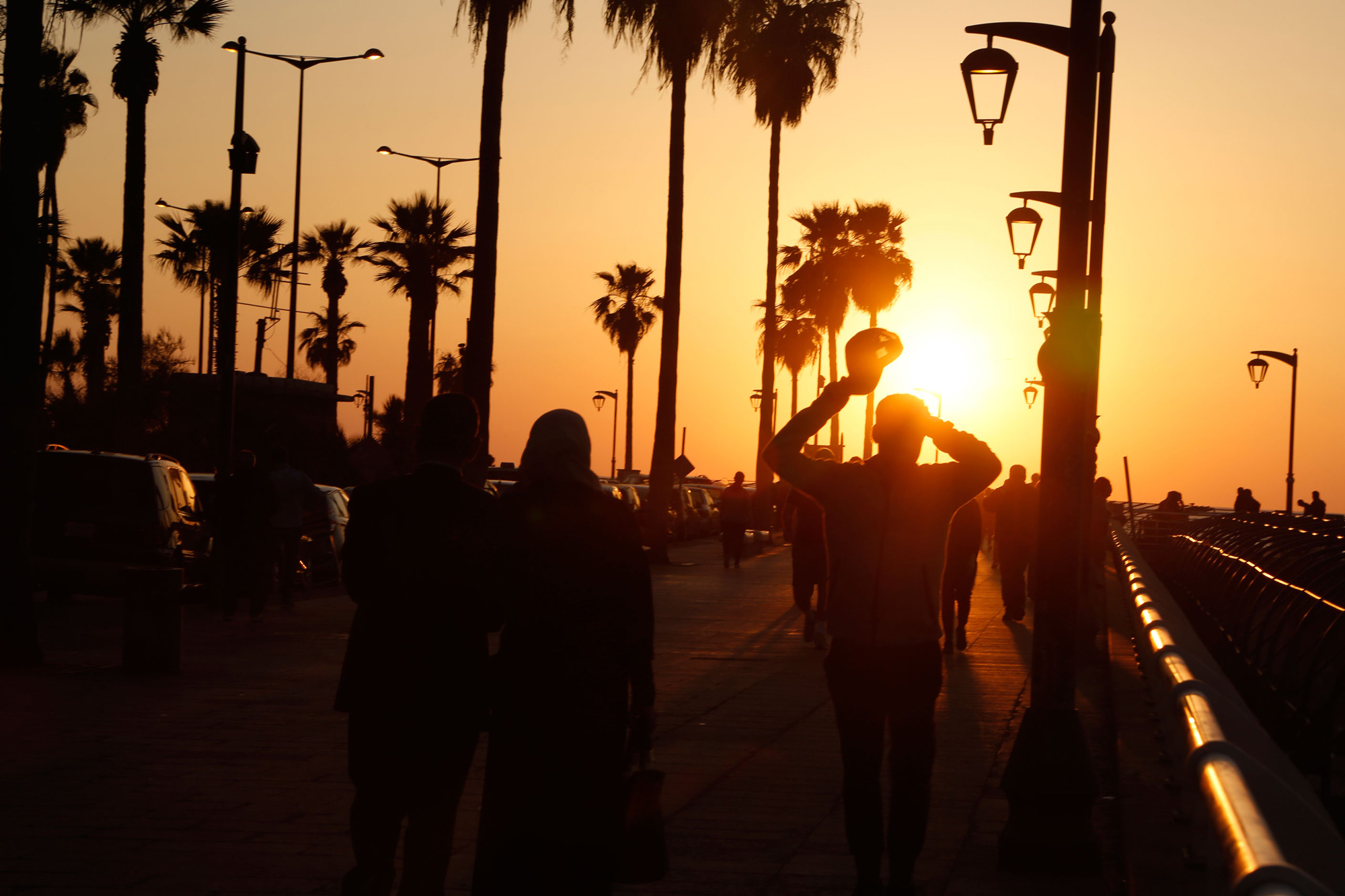 People walk along the corniche at sunset. 