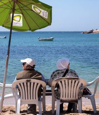 An elderly couple relax on Gleem Beach.