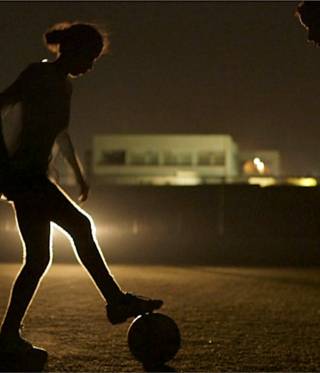 فتيات يلعبن كرة القدم على اضواء السيارات
