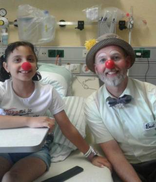 الطفلة المصابة في المستشفى برفقة ممرض بلباس مهرج